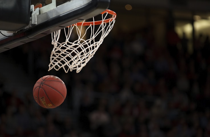 NBA篮球季后赛现场，球员激烈对抗扣篮瞬间，球场灯光聚焦在篮板上方